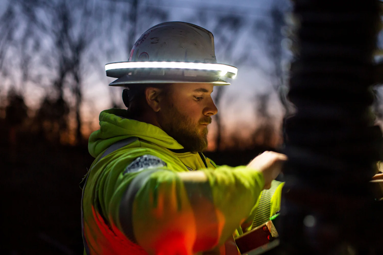 Worker in a high-visibility jacket and illuminated Halo directs activity on a jobsite